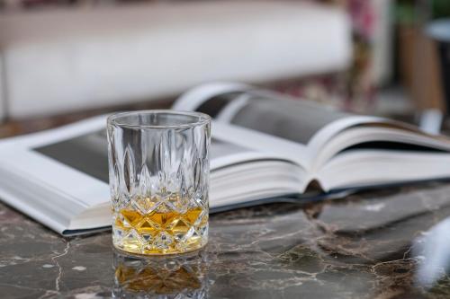 a glass of whiskey sitting on a table with an open book at Hotel im Auerbachtal in Bad Laasphe