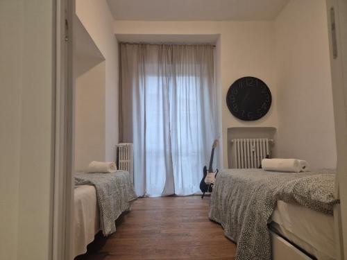 a bedroom with two beds and a clock on the wall at Centro Lecco Piazza Manzoni in Lecco