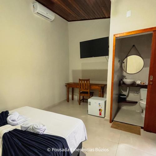 a room with a bed and a table and a bathroom at Pousada Emerências dos Búzios in Armacao dos Buzios
