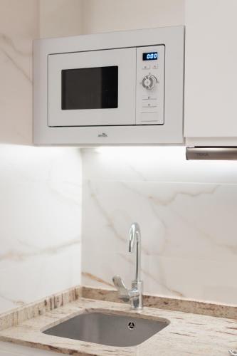 a microwave above a sink in a kitchen at Báelia Mini Casa Aurelia in Alicante
