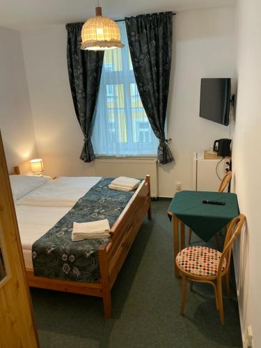a bedroom with a bed and a table and a window at Pension Abbazia in Františkovy Lázně