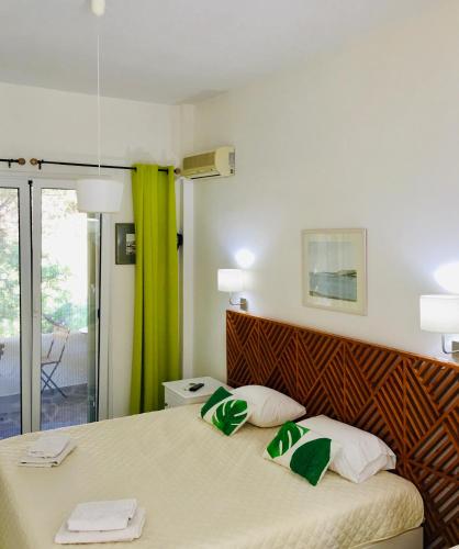 a bedroom with a bed with green and white pillows at Onar studios & residences in Pisses