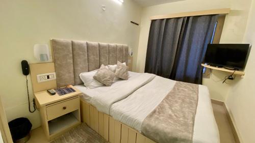 a small bedroom with a bed and a television at Hotel Meadows & Hotel Ocean Edge ! Family Hotel ! A couple Hotel ! Near to Hadimba Temple in Manāli
