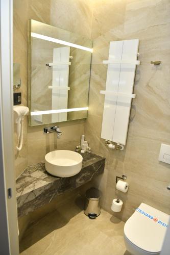 a bathroom with a sink and a toilet and a mirror at Hotel Ženeva Lux in Kragujevac