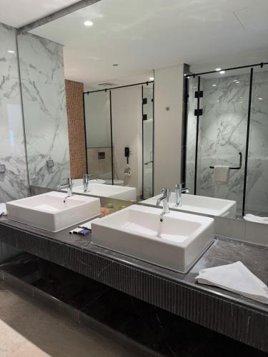 a bathroom with three sinks and a large mirror at The G Einbay Golf Resort in Ain Sokhna