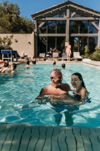 un homme et une femme dans une piscine dans l'établissement LA BASTIDE DE FANGOUSE, à Entrecasteaux