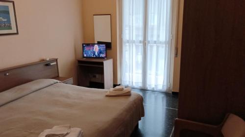 a hotel room with a bed and a television at Hotel Piccadilly in Varazze