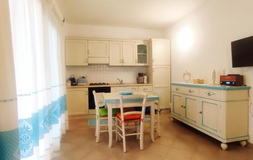Una cocina con gabinetes blancos y una mesa y sillas. en Casa Turchese, en Olbia