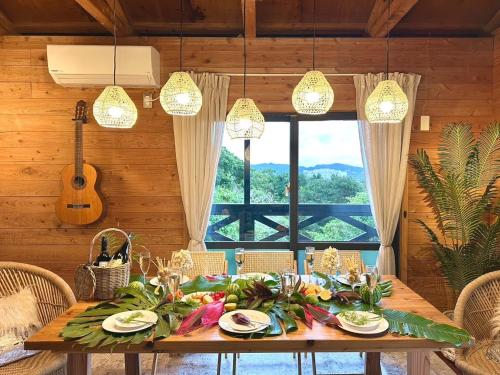 a dining room with a table with food and a guitar at 美ら海水族館まで車4分の一棟貸ヴィラちゅらジャングルリゾート in Motobu