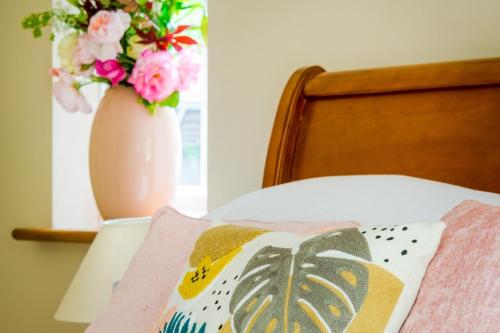 a vase filled with flowers sitting next to a bed at Rural Pet Friendly Apartment Near Salisbury in Winterbourne Dauntsey