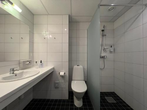a white bathroom with a toilet and a sink at Injoy Premium Hotel Solna in Solna