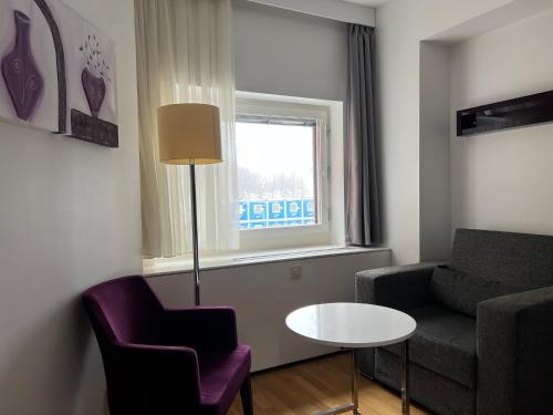 a living room with a couch and a table and a window at Injoy Premium Hotel Solna in Solna