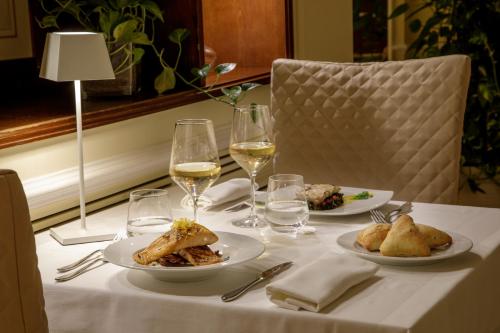 a table with two plates of food and glasses of wine at Donna Laura Palace by OMNIA hotels in Rome