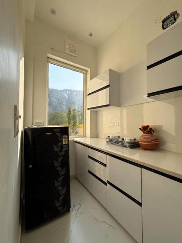 a kitchen with a black refrigerator and a window at Essence Of Sariska in Alwar