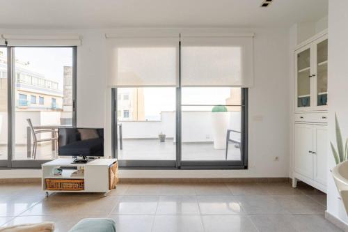 a living room with large windows and a tv at Apartamento Sunshine Grao in Burriana