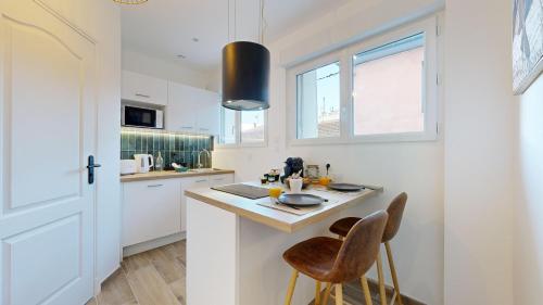 - une cuisine blanche avec une table et deux chaises dans l'établissement expat renting - Le Tropical - Netflix - Proche gare, à Toulouse