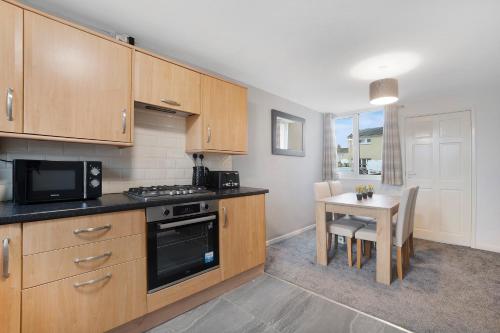 a kitchen with wooden cabinets and a table with a microwave at NEW! 3BR in Traynor Square in Catterick Bridge Station