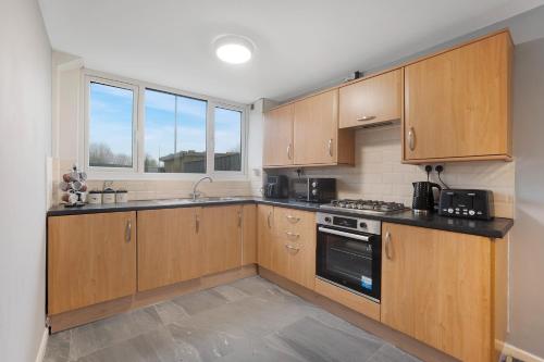 a kitchen with wooden cabinets and a stove at NEW! 3BR in Traynor Square in Catterick Bridge Station