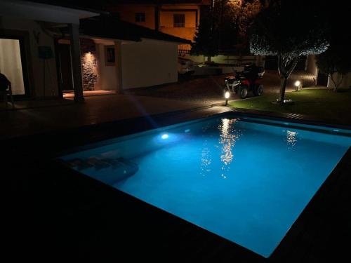 a blue swimming pool in a yard at night at Campeã Valley in Campeã