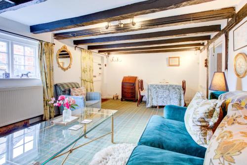 a living room with a blue couch and a glass table at Eglantine in Crondall