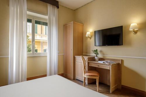 a bedroom with a bed and a desk and a television at Hotel Santa Costanza by OMNIA hotels in Rome