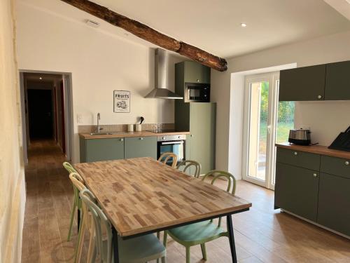 a kitchen with a wooden table and chairs at La maison du pin in Les Salles-de-Castillon