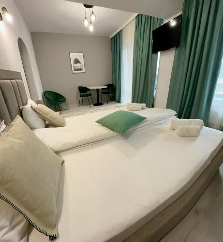 two large beds in a room with green curtains at Hotel Green House in Craiova