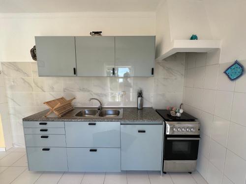 a kitchen with white cabinets and a sink and a stove at Ceu Azul - Elevated apartment with stunning views and big garden - Somewhere Special in Tavira