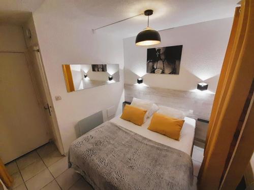 - une chambre avec un lit et 2 oreillers jaunes dans l'établissement Appartement Village naturiste Leather, au Cap d'Agde