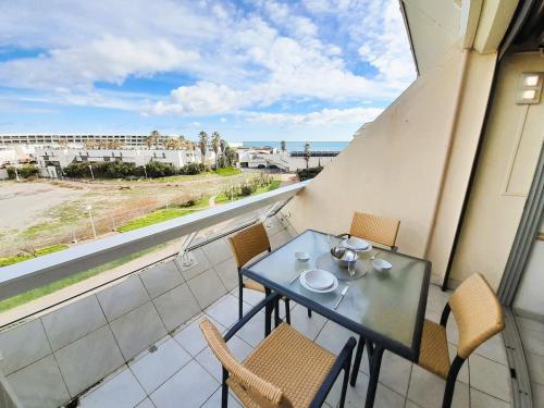 un balcon avec une table et des chaises et une vue sur l'océan dans l'établissement Appartement Village naturiste Leather, au Cap d'Agde