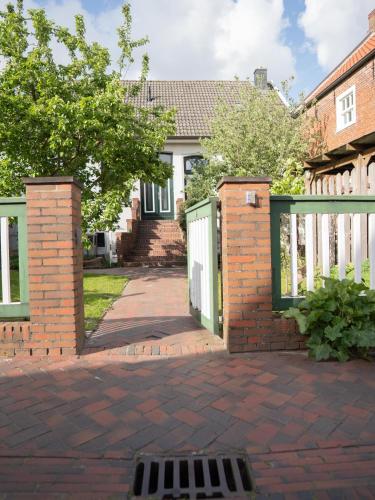 a white fence with a gate and a brick driveway at Faehrmann-s-Huus-Ditzum in Ditzum