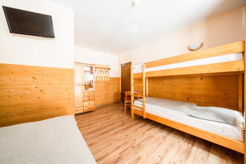 two bunk beds in a room with wooden walls at Schronisko PTTK Orlica in Szczawnica