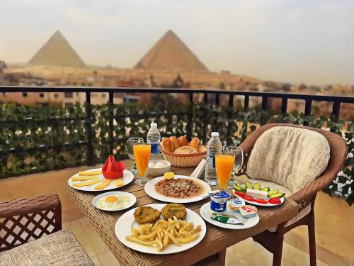 a table with plates of food and the pyramids at The Pyramids Crypt Inn in Cairo