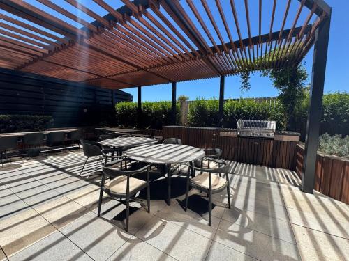 a patio with a table and chairs under a wooden pergola at Box Hill luxury 29th floor apartment with car park in Box Hill