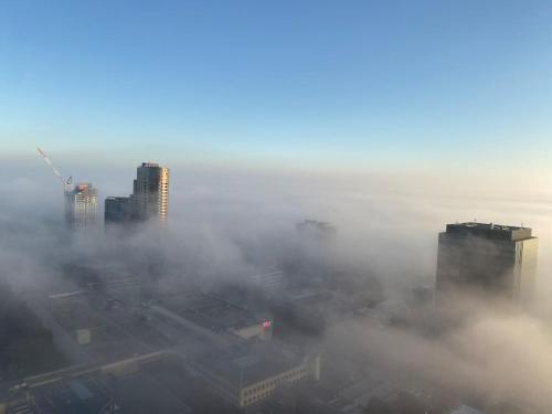 an aerial view of a city in the fog at Box Hill luxury 29th floor apartment with car park in Box Hill