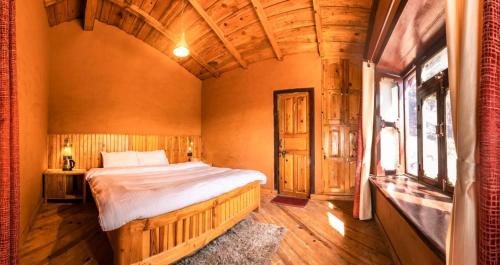 a bedroom with a bed in a room with wooden ceilings at Odyssey Stays Jageshwar Dham in Panuānaula