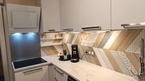 une cuisine avec des placards blancs et une cafetière sur un comptoir dans l'établissement Reims Centre Deluxe Suite, à Reims