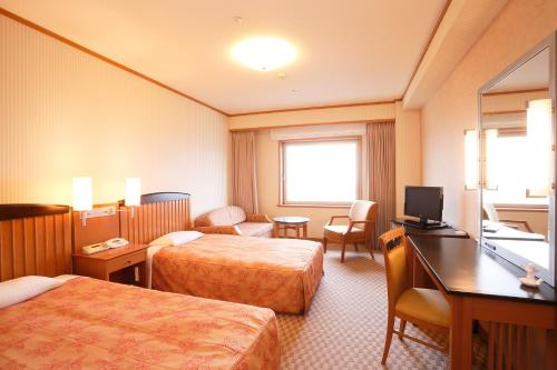 um quarto de hotel com duas camas e uma secretária em Aeria Tohno em Tōno