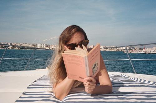 a woman sitting on a boat reading a book at Relais Corte Palmieri & Il Chiostro - Residenza d'epoca in Gallipoli