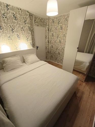 Cette chambre comprend un grand lit blanc et du papier peint. dans l'établissement Reims Centre Deluxe Suite, à Reims