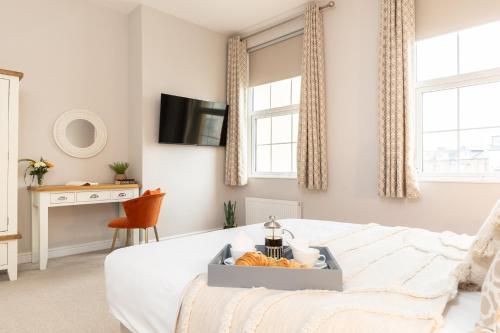 a bedroom with a bed and a desk and windows at The Clarence Gardens Hotel, BW Signature Collection in Scarborough