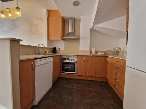 a kitchen with wooden cabinets and white appliances at La Tranquilidad en Sabadell in Sabadell