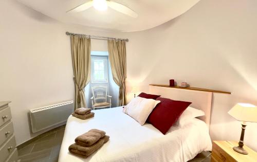 een slaapkamer met een wit bed met rode kussens bij Gîtes Château de la Selve in Grospierres