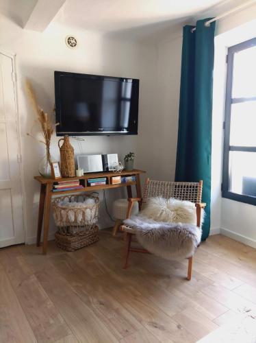 a living room with a tv and a chair at A l'Ombre de la Dame in Cucuron