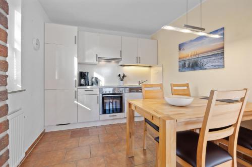 eine Küche und ein Esszimmer mit einem Holztisch und Stühlen in der Unterkunft Ferienhaus Kristina in Hooksiel