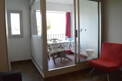 Cette chambre dispose d'une chaise rouge, d'une table et d'une fenêtre. dans l'établissement Studio CAP D 'AGDE CT150-D210, au Cap d'Agde
