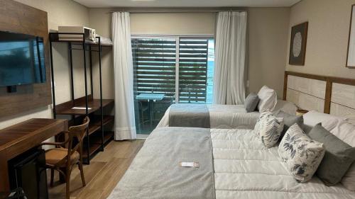 a bedroom with a bed and a desk and a television at Hotel VillaReal Charme in Guaratuba