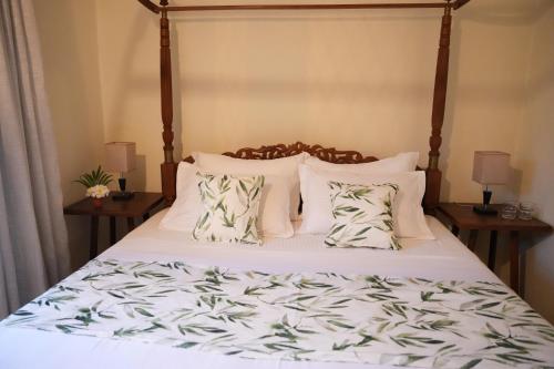a bedroom with a bed with white sheets and pillows at La'Litha Villa in Bentota