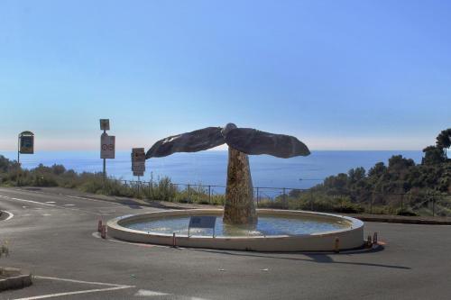 a statue in the middle of a road near the ocean at Le Mimose Terrace in Bordighera