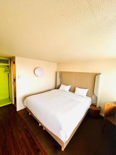 a bedroom with a large white bed and a green door at Campanile Montargis - Amilly in Amilly